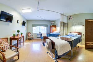 Double occupancy room with chairs, flat screen tv, large window, and decorative table