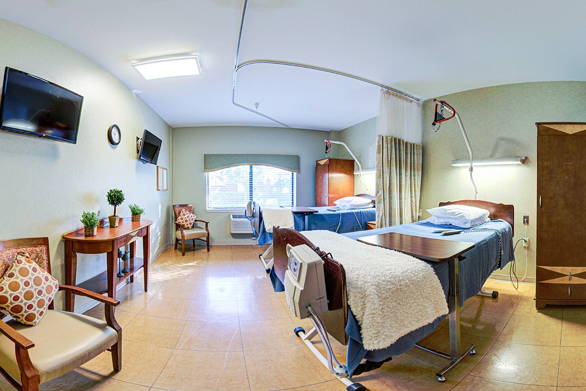 Double occupancy room with chairs, flat screen tv, large window, and decorative table