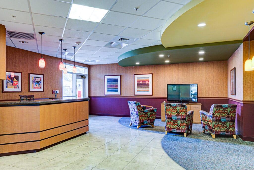 Lobby with reception desk, colorful club chairs and flat screen TV