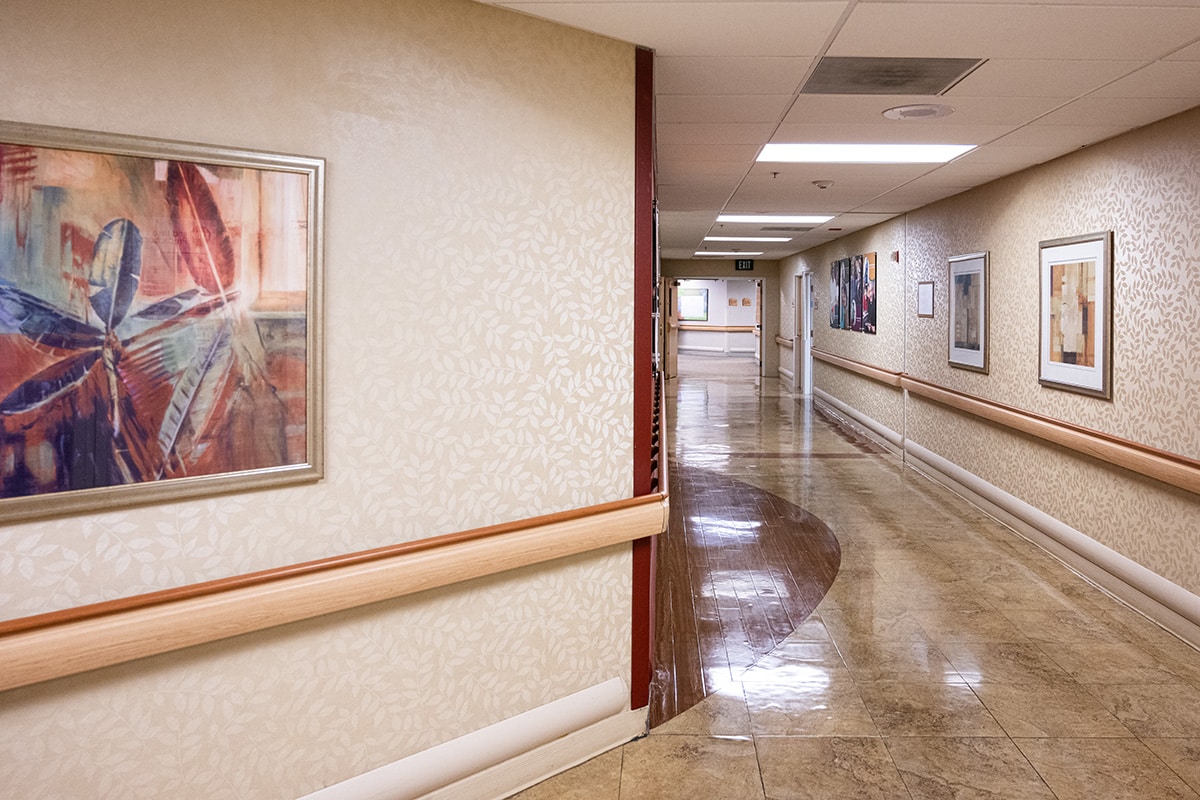 Wide hallway with tile floors and framed artwork on the walls.