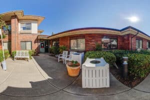 Courtyard outside with bench and chairs amongst greenery
