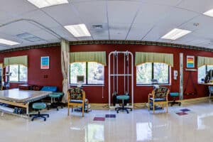 Rehab gym with four large windows and other physical therapy equipment.