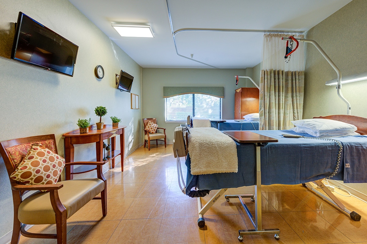 Double occupancy room facing flat screen tv and large window, with beds.