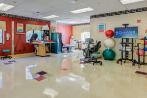 Rehab gym with TV, colorful balls, and other physical therapy equipment