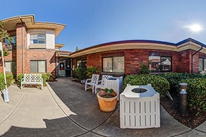 Courtyard outside with bench and chairs amongst greenery