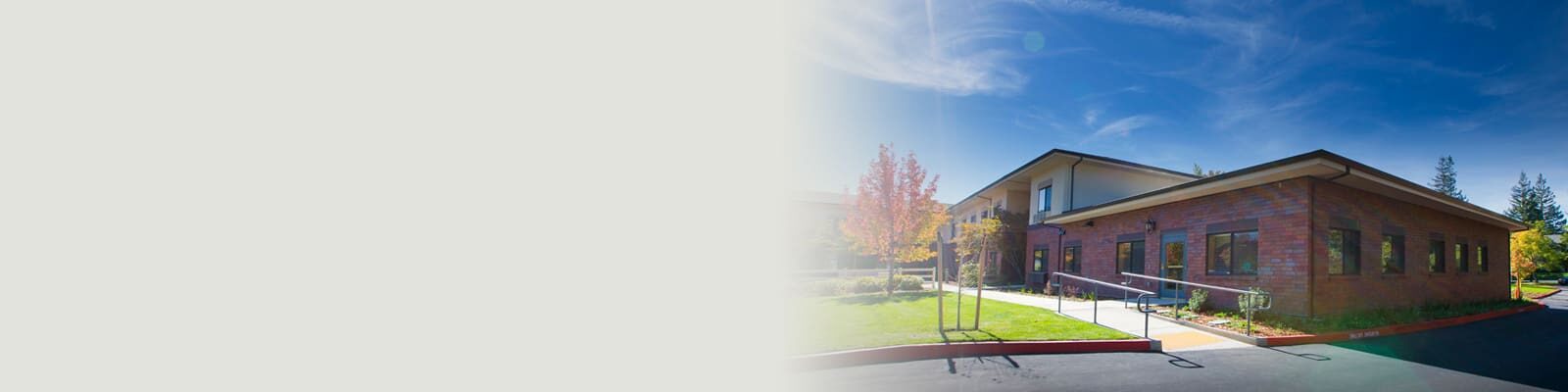 The front outside the front of the facility amongst greenery, and blue sky
